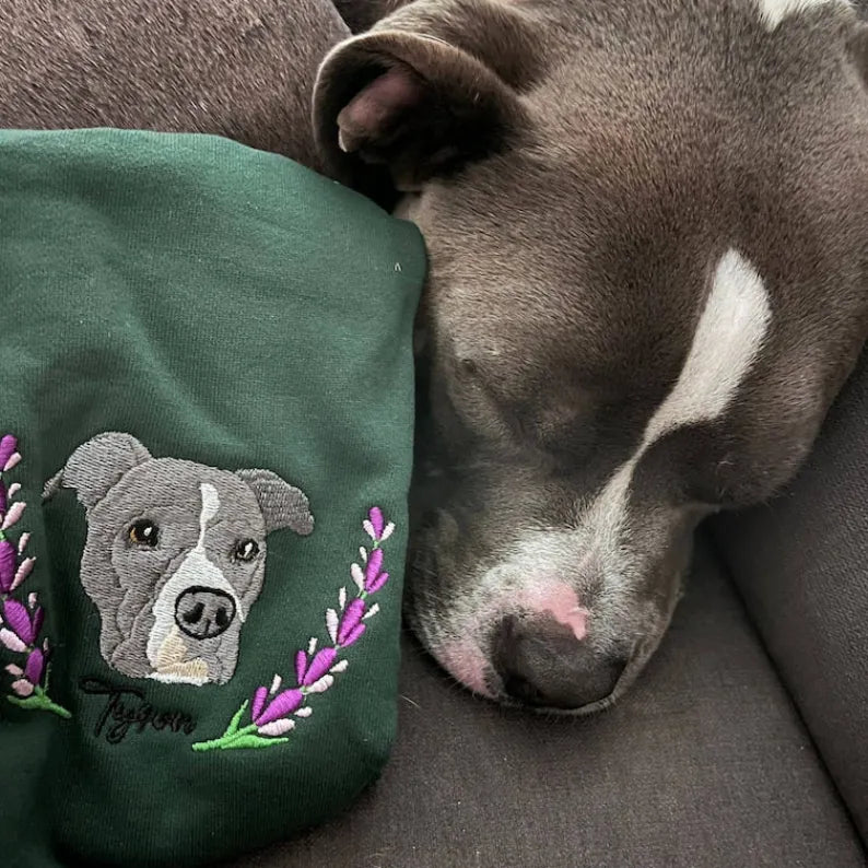 Dog resting beside a custom embroidered pet portrait on green clothing